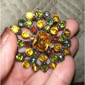Amber, red, yellow and green stones on a coppery-toned background brooch